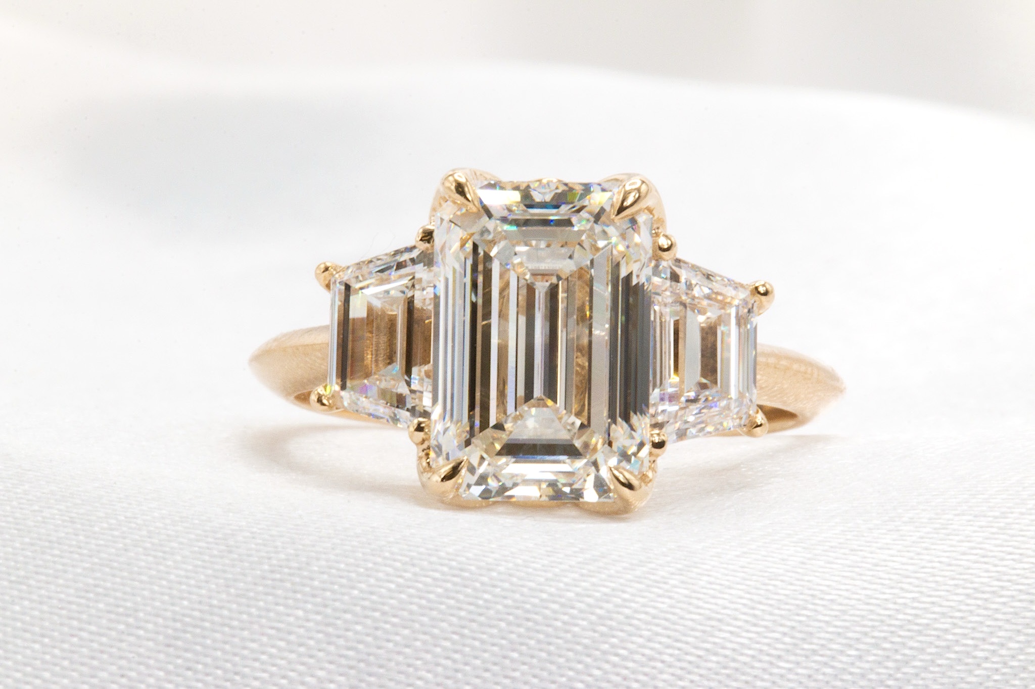 Ring with a large rectangular central gemstone and smaller side stones, set in a gold band.