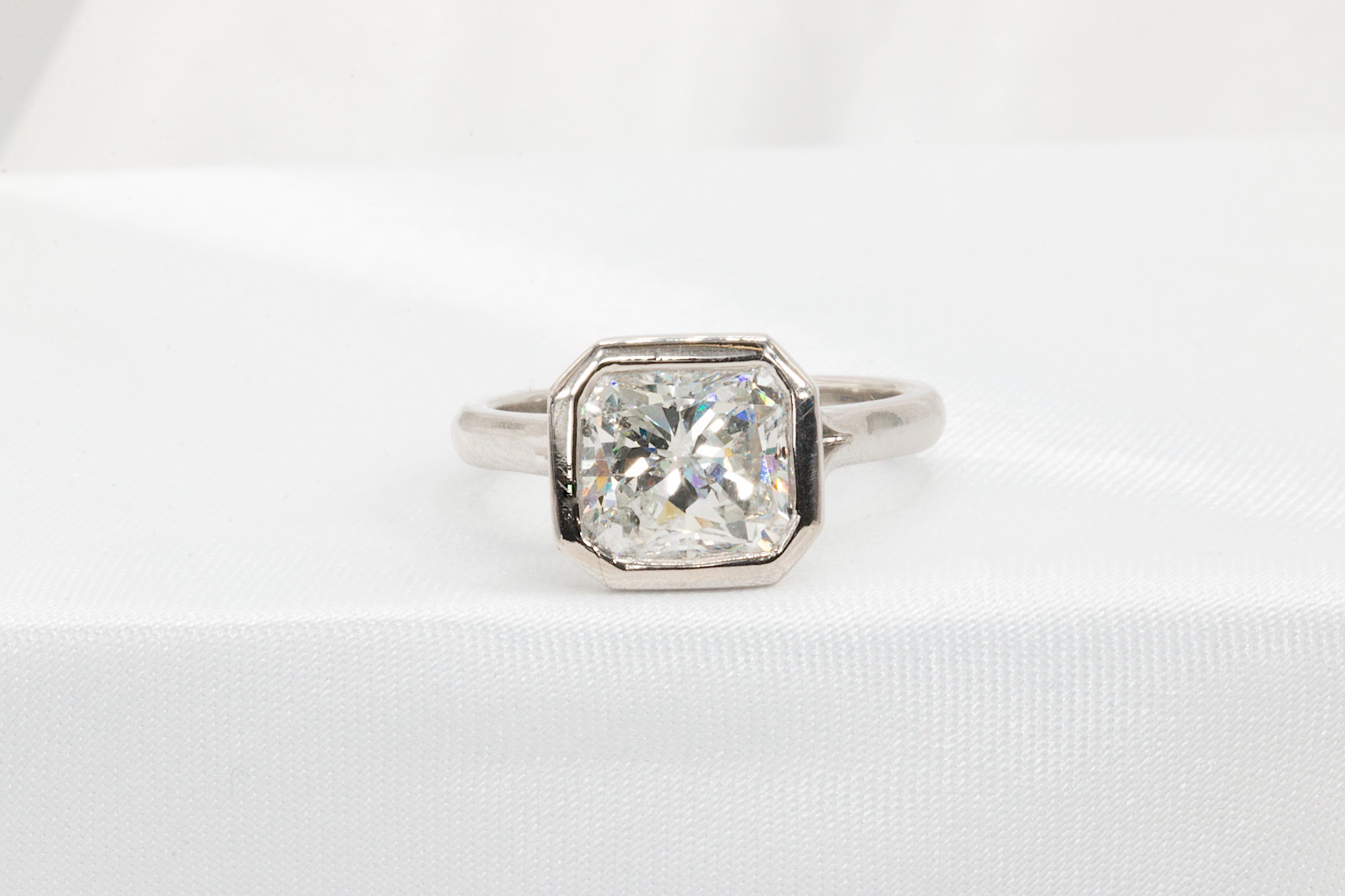 Ring with a large, square-cut gemstone set in a silver band, displayed on white fabric