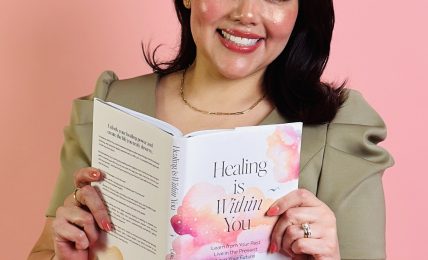 Smiling woman holding a book titled 'Healing is Within You' against a pink background.