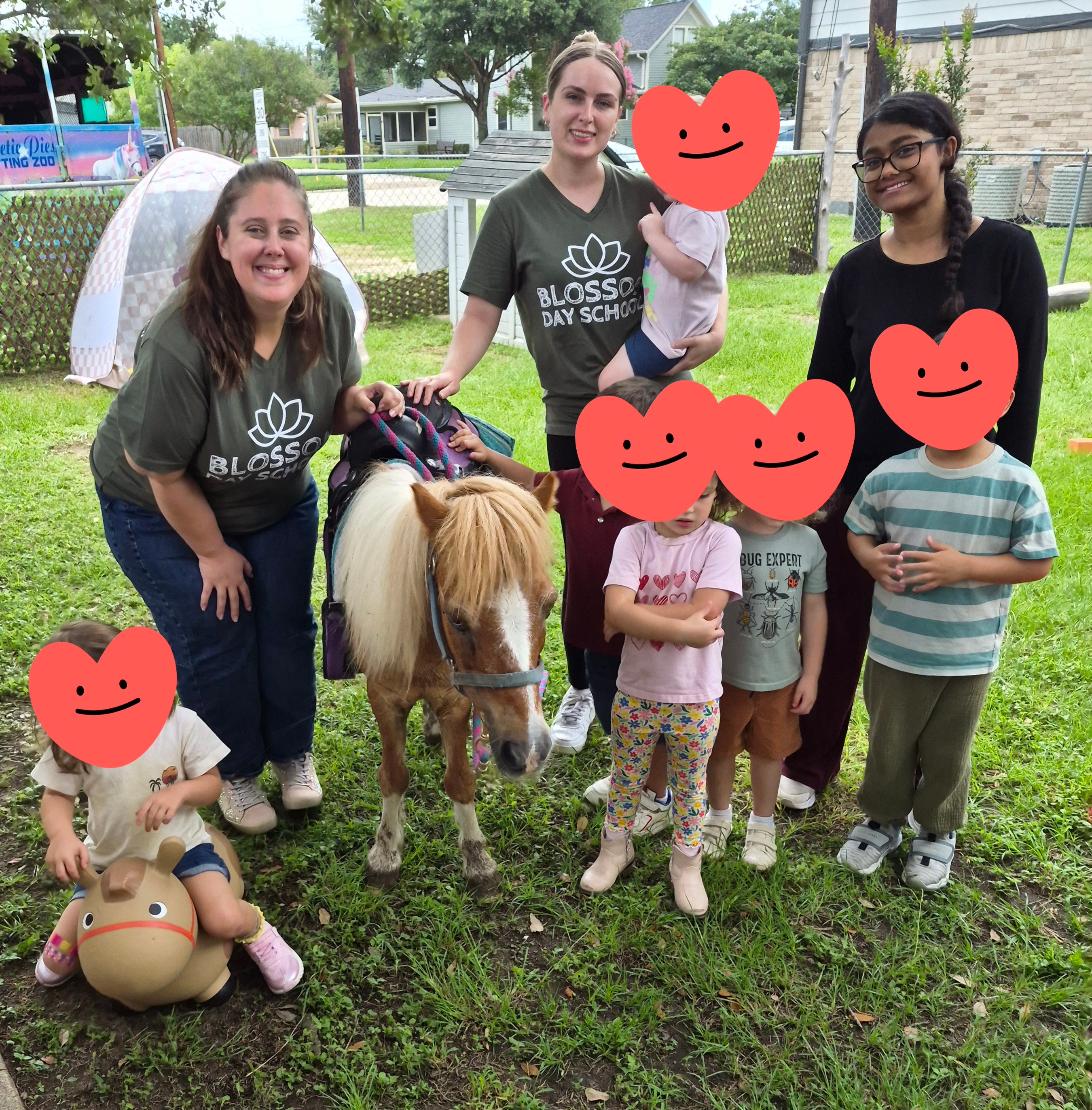 Group of children and two adults with a pony outdoors, some children holding plush toys, in a grassy area with trees.